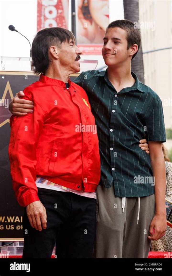 Anthony Kiedis, left, of the Red Hot Chili Peppers of sits with model