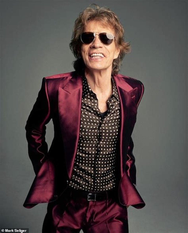 Sir Mick Jagger, 80, battles strong winds as he arrives at King Charles